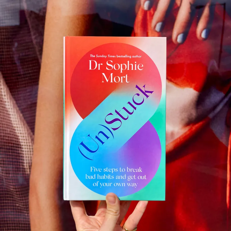 A copy of (Un)Stuck by Dr Sophie Mort held in two hands